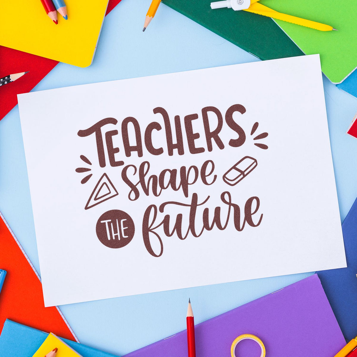 Brown teacher stamp and seal reading Teachers Shape the Future on white card, framed by colorful pencils and notebooks.
