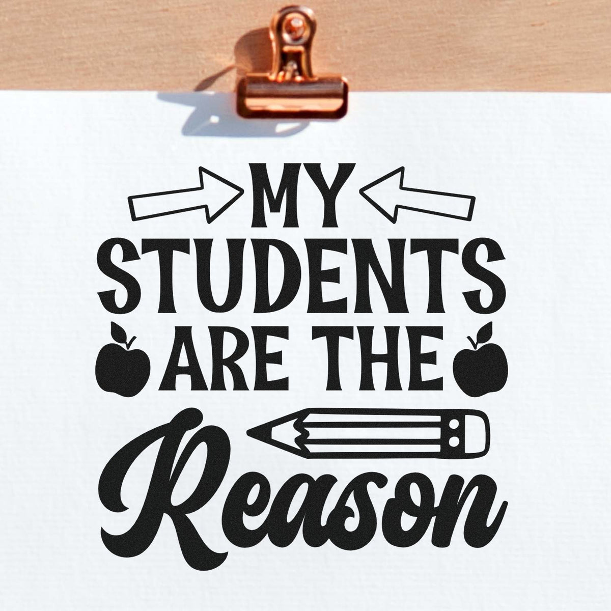 Copper clip displays a black custom stamp and seal design reading My Students Are the Reason with arrows, apples, and a pencil.