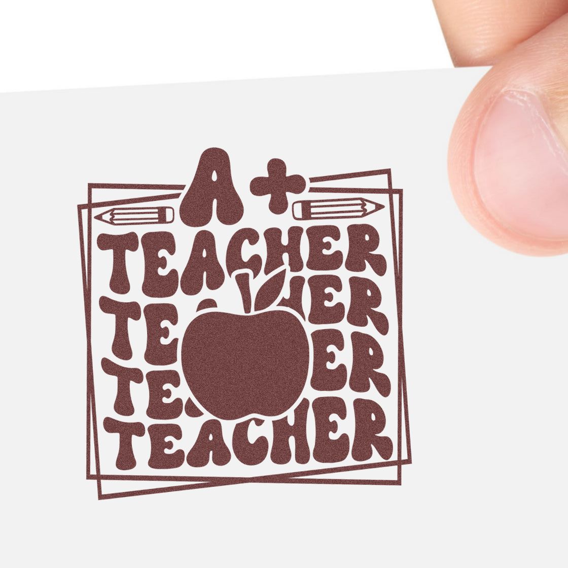 Burgundy teacher stamp seal with apple, pencils, and retro text on white card held by hand.
