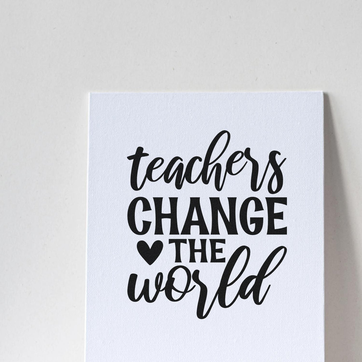 Black teacher stamp and seal on white textured card reading teachers change the world with a heart.