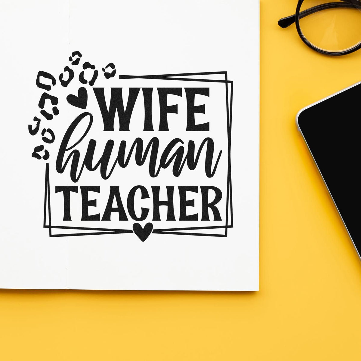Black wife human teacher stamp with leopard print and heart on white paper, beside glasses and phone on yellow background.