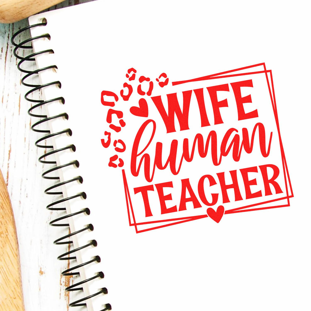 Red Wife Human Teacher custom stamp seal with hearts on a white notebook beside black spiral binding