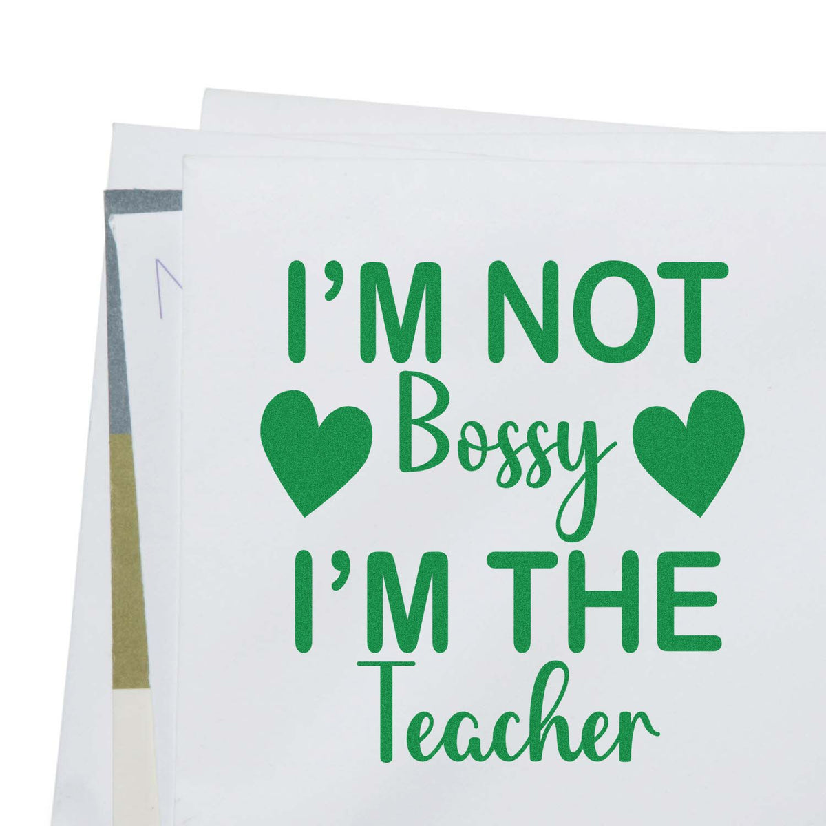 Green stamp-style teacher quote with hearts on white paper: Im not bossy, Im the teacher.
