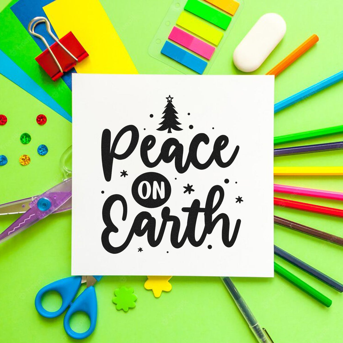 Black Peace on Earth stamp and seal on a white card, surrounded by colorful stationery on a bright green background.
