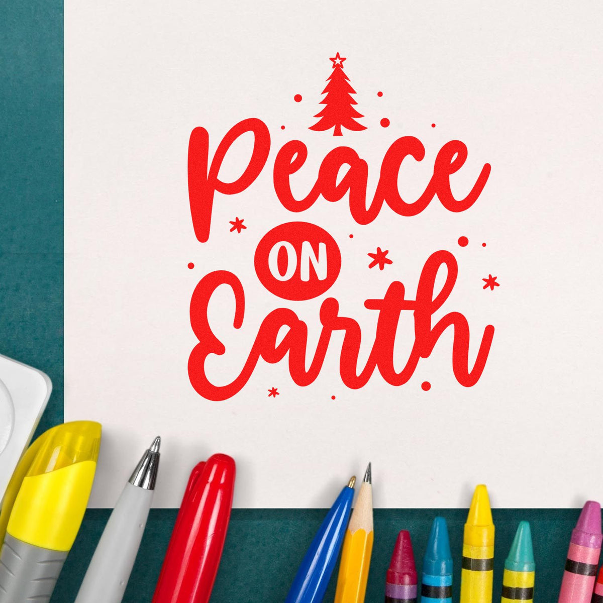 Red Peace on Earth holiday stamp and seal design with Christmas tree on white paper, surrounded by colorful pens.