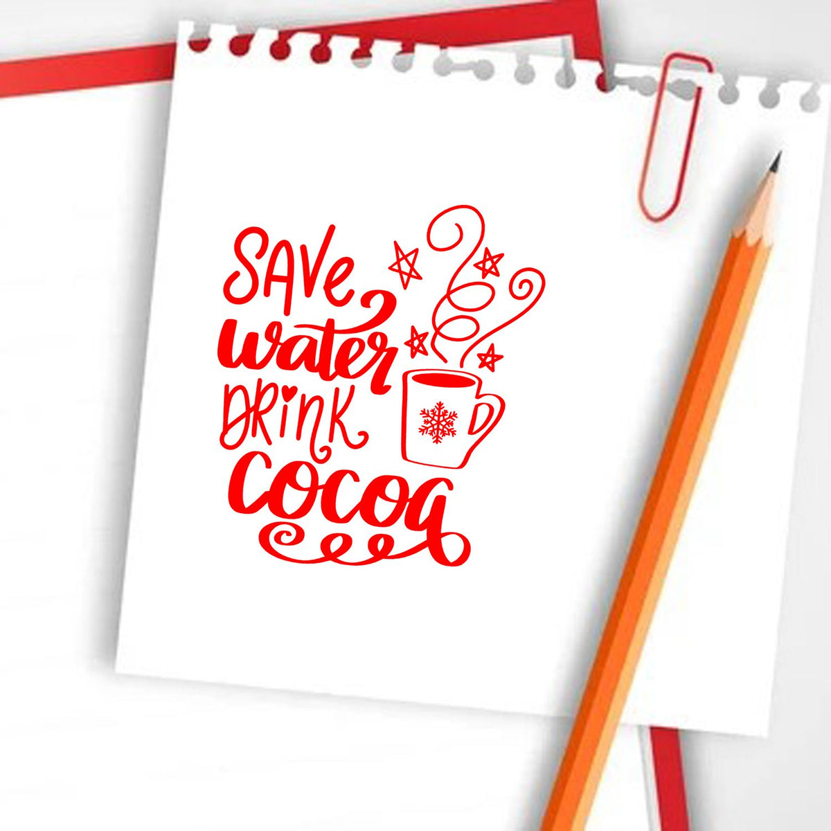 Red decorative stamp reading Save water drink cocoa on white notepad paper with pencil and paperclip.