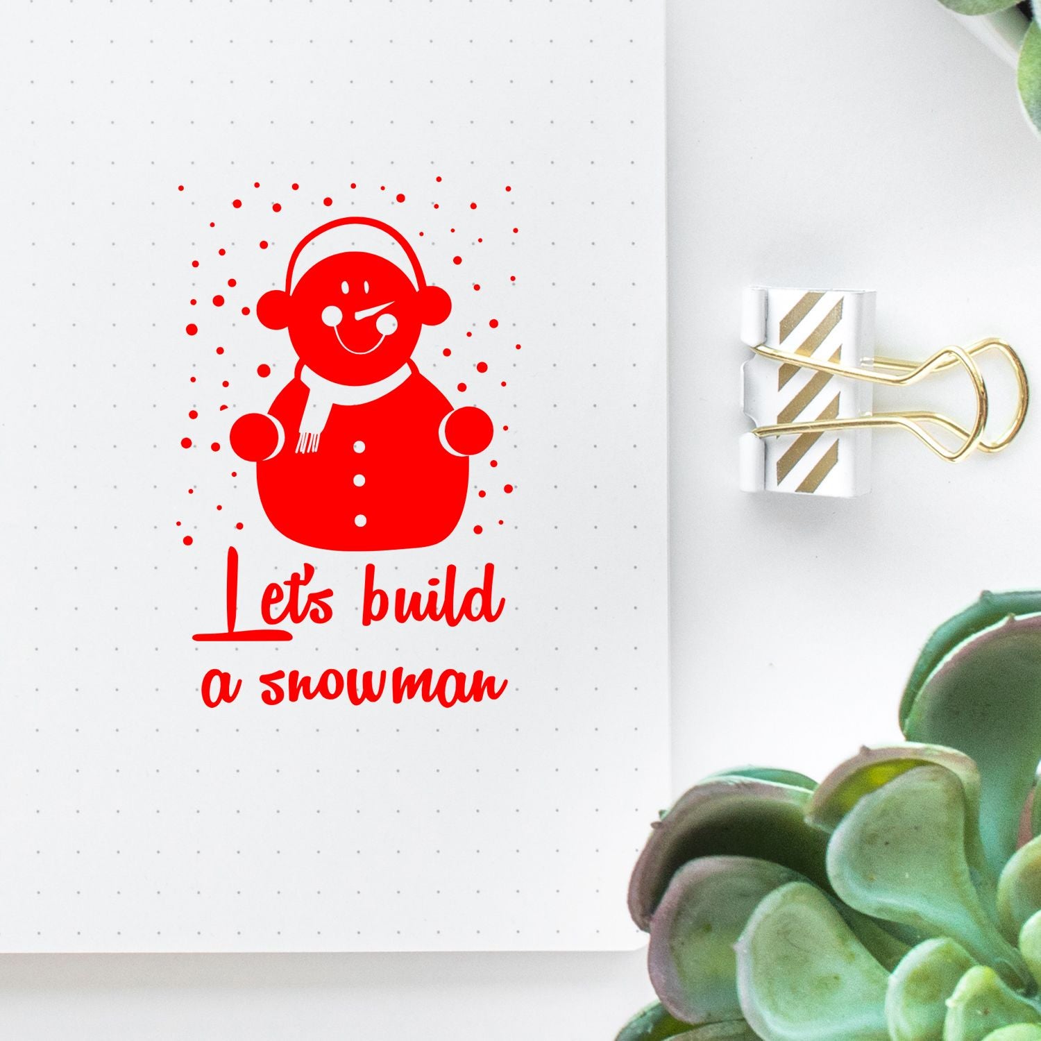 Red snowman stamp with Lets build a snowman on white dotted paper, paired with a gold-striped binder clip seal