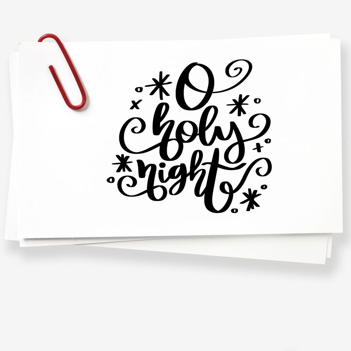 Black O holy night holiday stamp design on stacked white paper with a red paperclip and star accents.