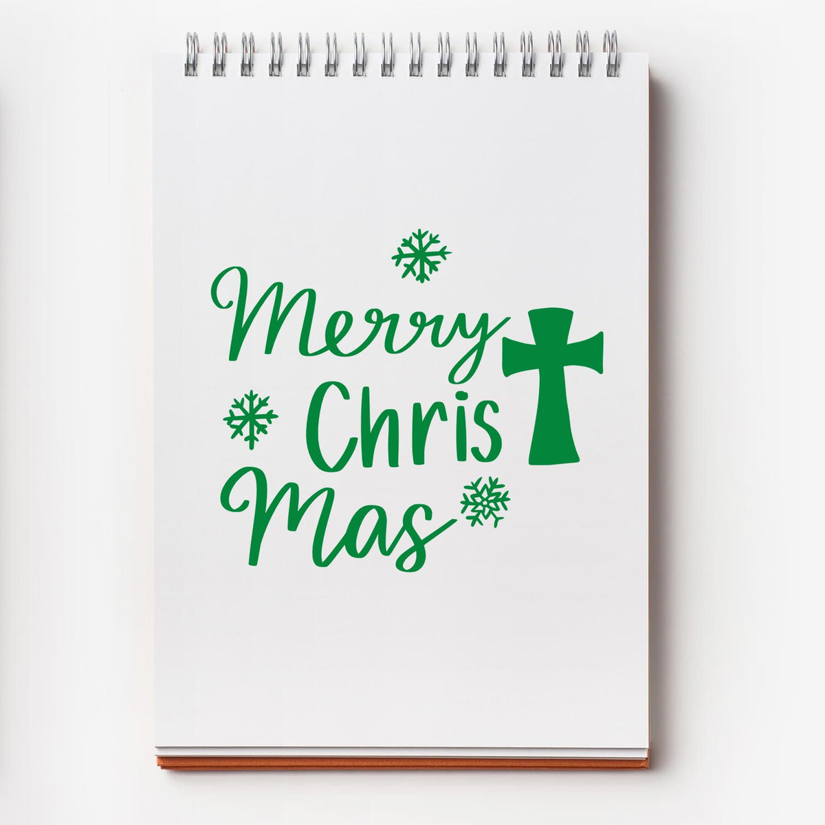 Green Merry Christmas stamp/seal design with cross and snowflakes on a white spiral notepad