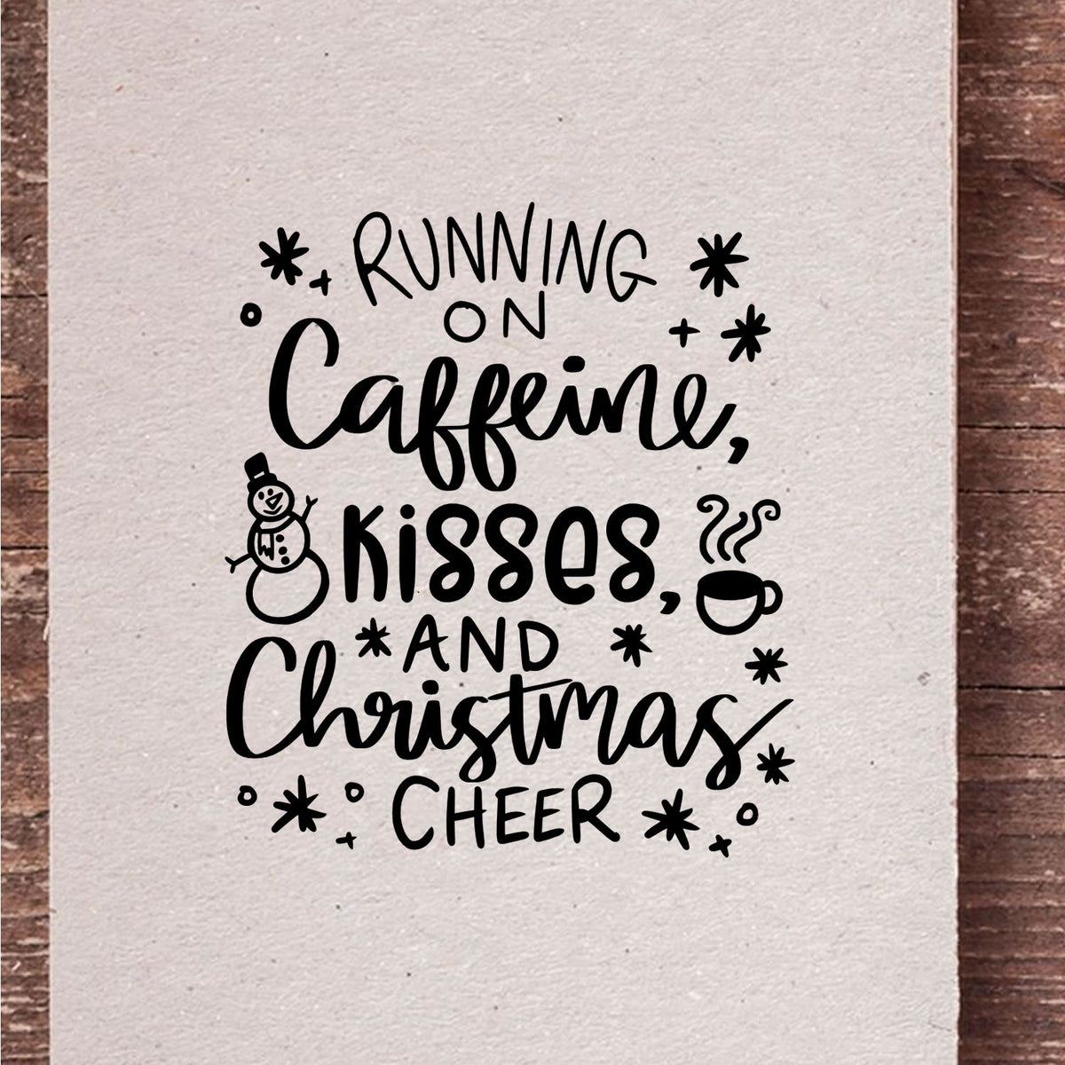 Black holiday stamp and seal on cream paper reading Running on Caffeine, kisses, and Christmas cheer, with snowman and coffee icons.
