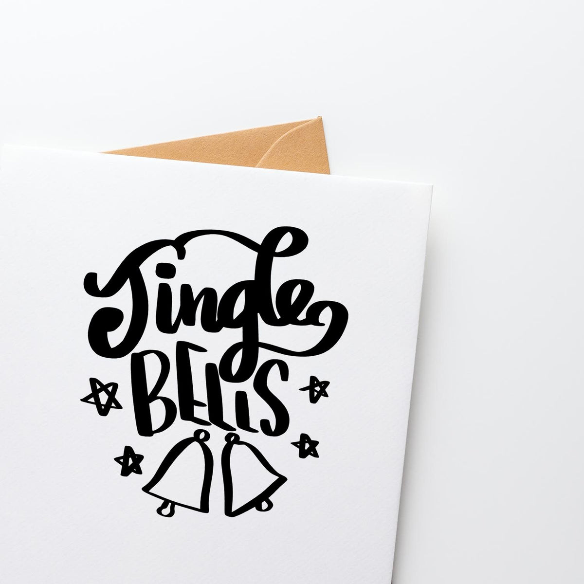 Black Single Bells stamp and seal design with bells and stars on a white card, tan envelope peeking behind.