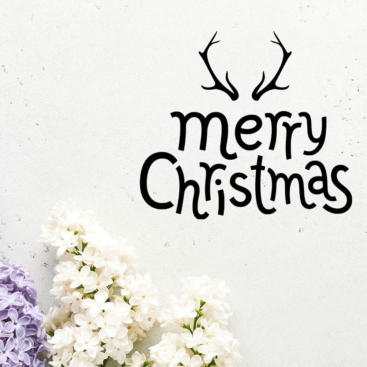 Black Merry Christmas stamp with antlers on a white background, accented by white and lilac flowers.