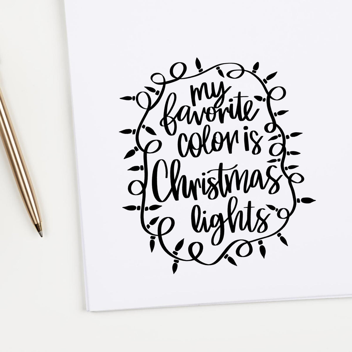 Black holiday stamp-and-seal design reading my favorite color is Christmas lights, framed by string lights on white paper.