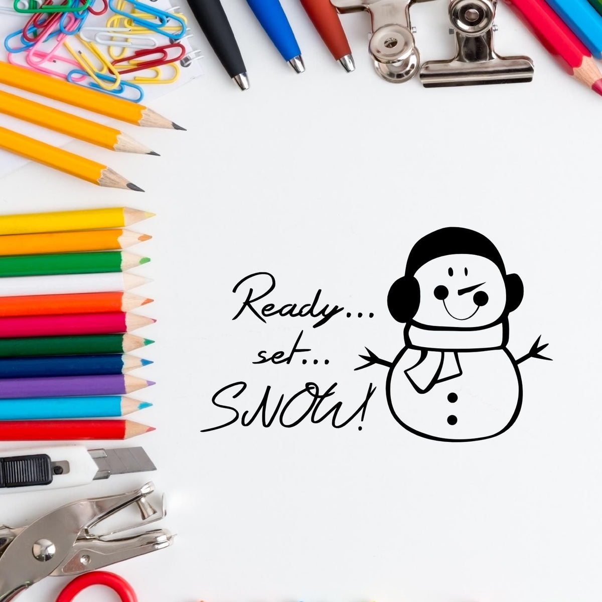 Colorful stationery and metal stamps/seals frame a black snowman stamp with Ready... set... Snow! on a white background.