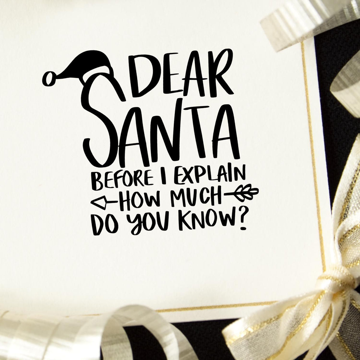 Black holiday stamp/seal reading Dear Santa...How much do you know? on white card with gold-and-white ribbon.