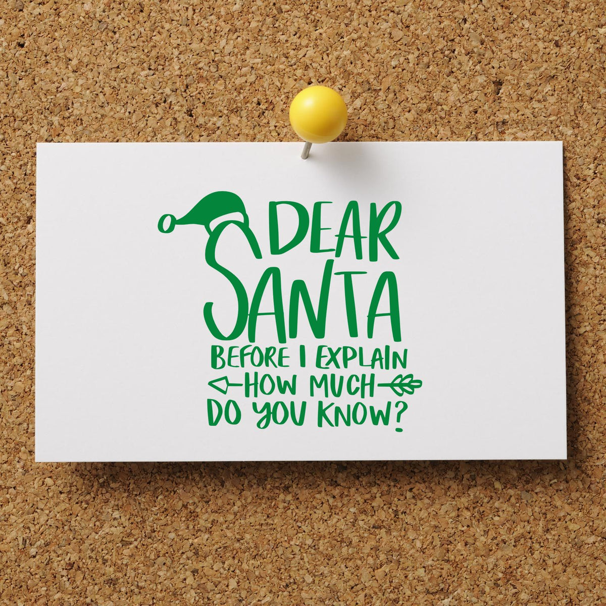 Green Santa stamp design on white card pinned to corkboard with yellow pushpin, featuring festive lettering.