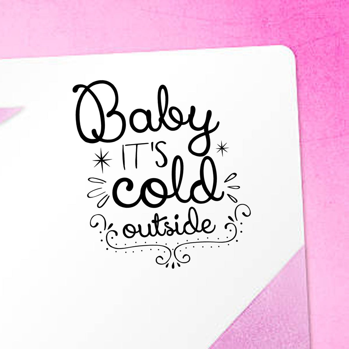 Decorative black stamp seal reading Baby its cold outside on a white card with a pink background.