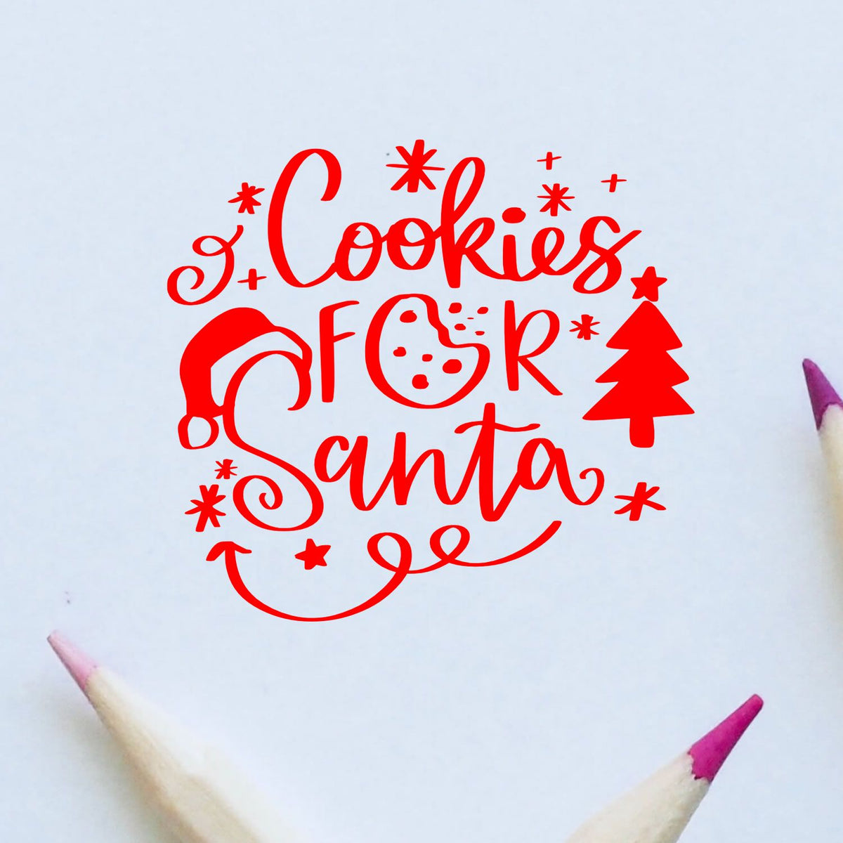 Red Christmas cookie stamp design reading Cookies for Santa with tree, stars, cookie and white background, pencil tips visible.