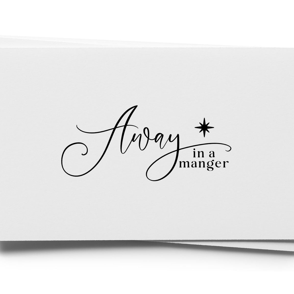 Black Christmas stamp and seal reading Away in a manger with a star, in black on white paper.