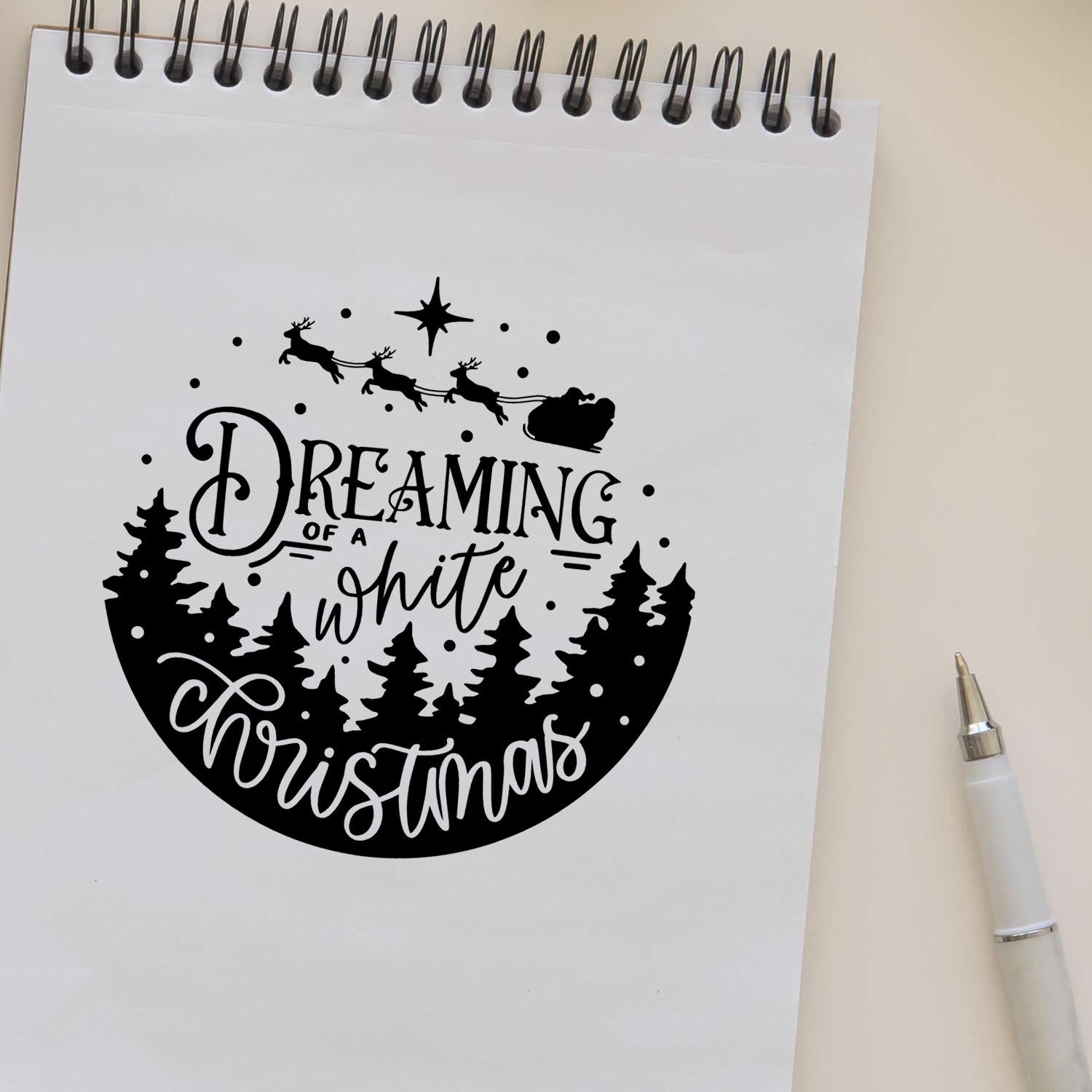 Black Christmas stamp and seal design on white paper, with Santa sleigh, pine trees, and Dreaming of a white Christmas text.