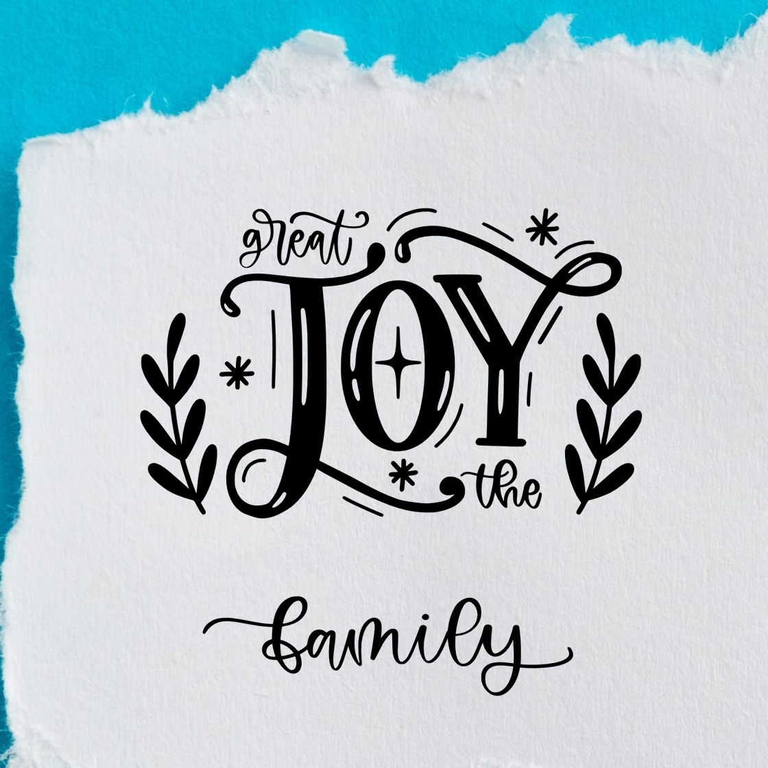 Black decorative stamp/seal reading great JOY the family with leafy accents on white paper and turquoise background.