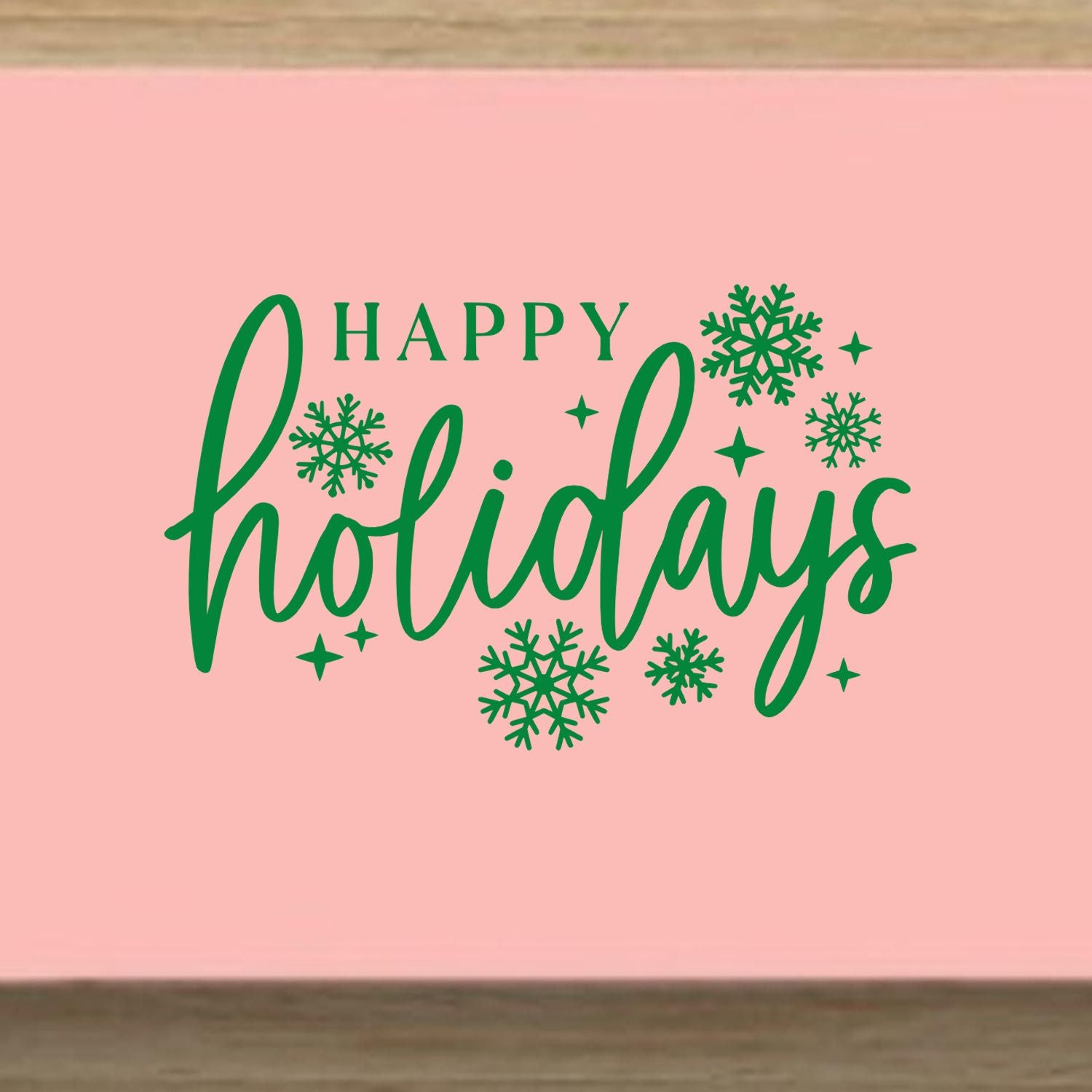 Pink holiday stamp seal with green Happy Holidays script, snowflakes, and sparkles.
