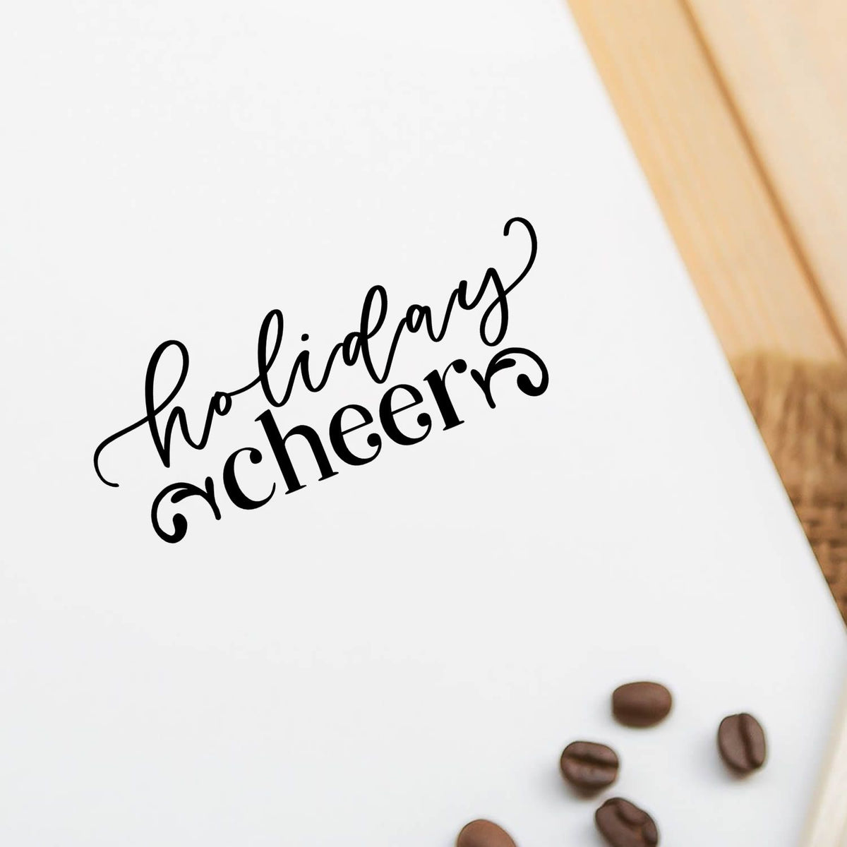 Black Holiday cheer stamp/seal on white card with brown coffee beans and a light wood edge