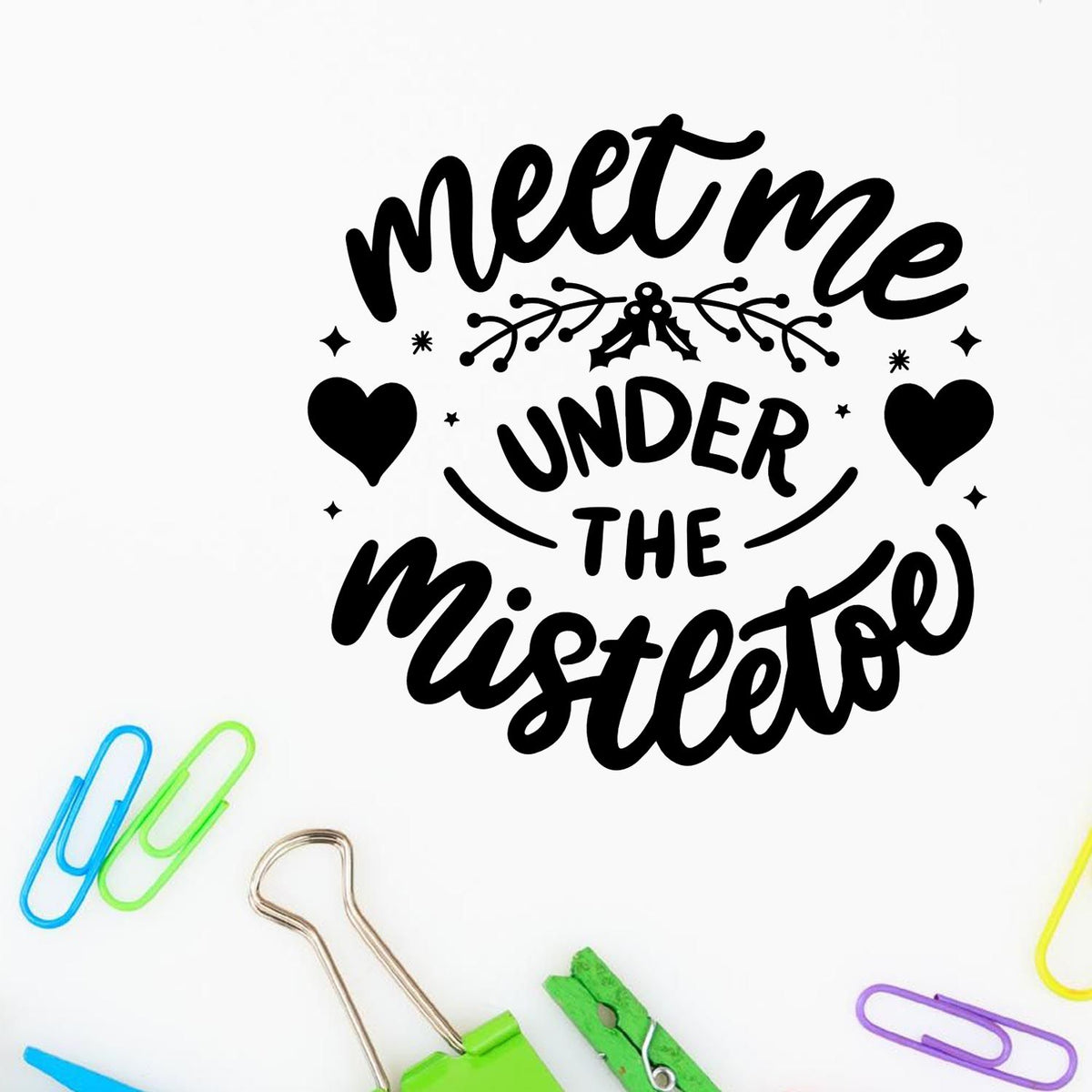 Black holiday stamp and seal design reading Meet Me Under the Mistletoe with hearts, mistletoe, on white with colorful paper clips.