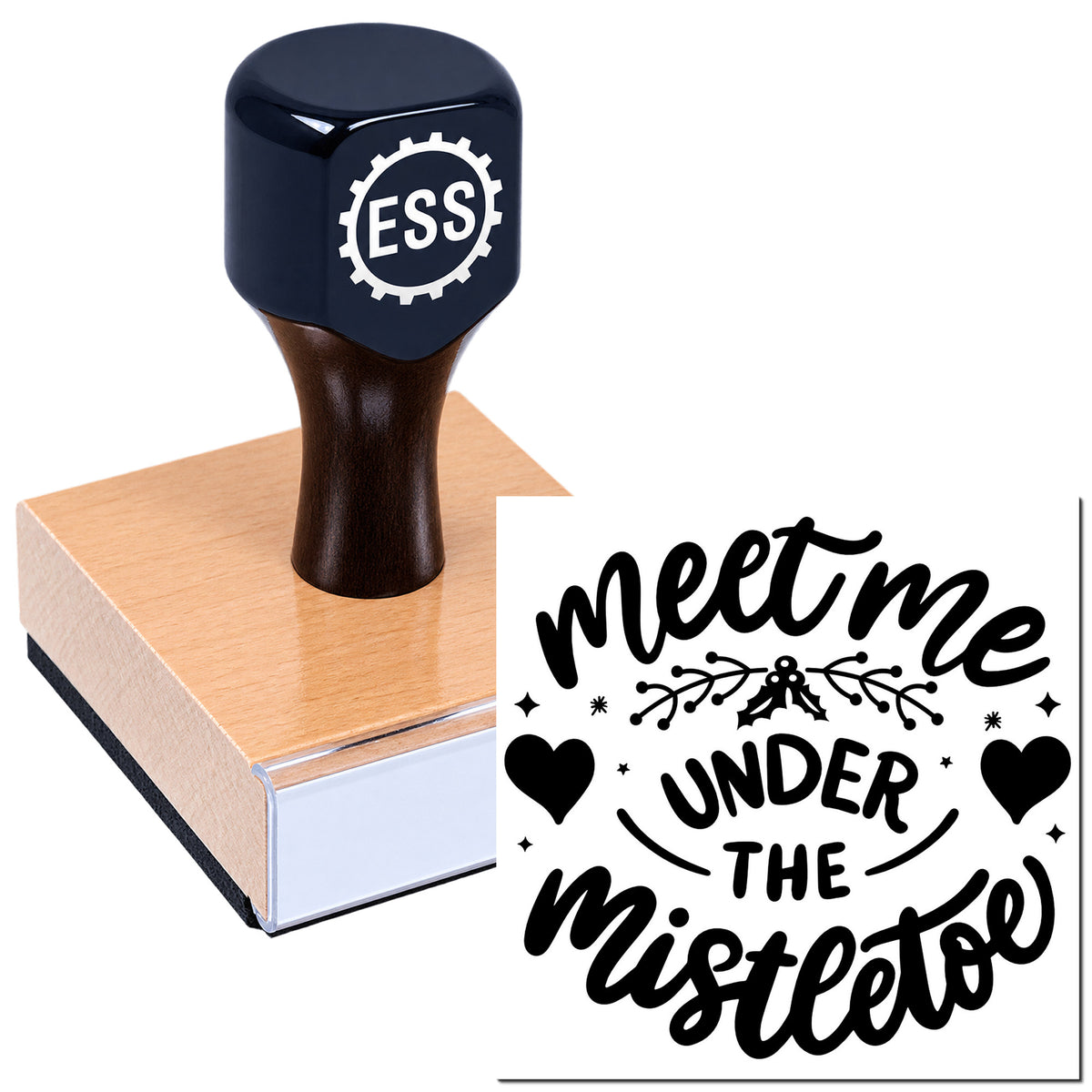 Dark blue ESS stamp and seal on a pink wooden block, printing black "meet me under the mistletoe" text with hearts and holly.