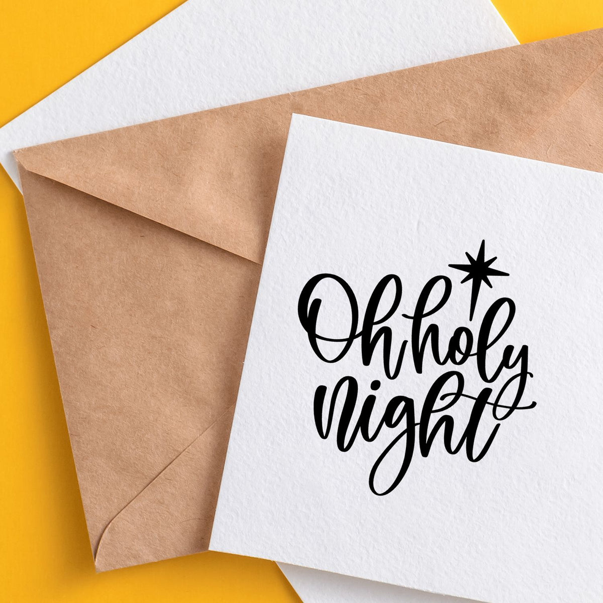Black Oh Holy Night stamp and seal on white card beside brown envelope, set on a bright yellow background.