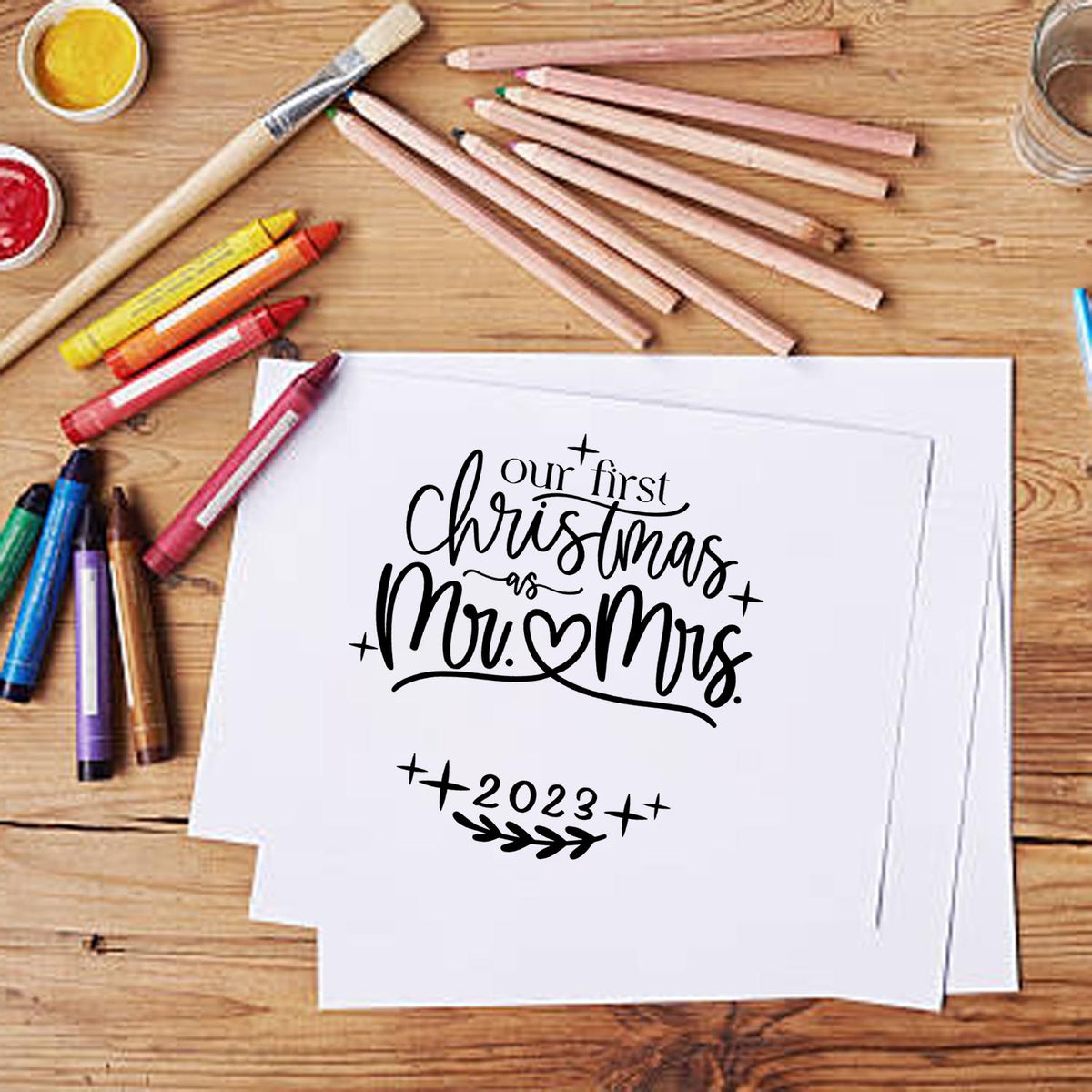 Custom stamp and seal design for Our First Christmas as Mr. & Mrs. 2023 on white paper, with pencils and markers.