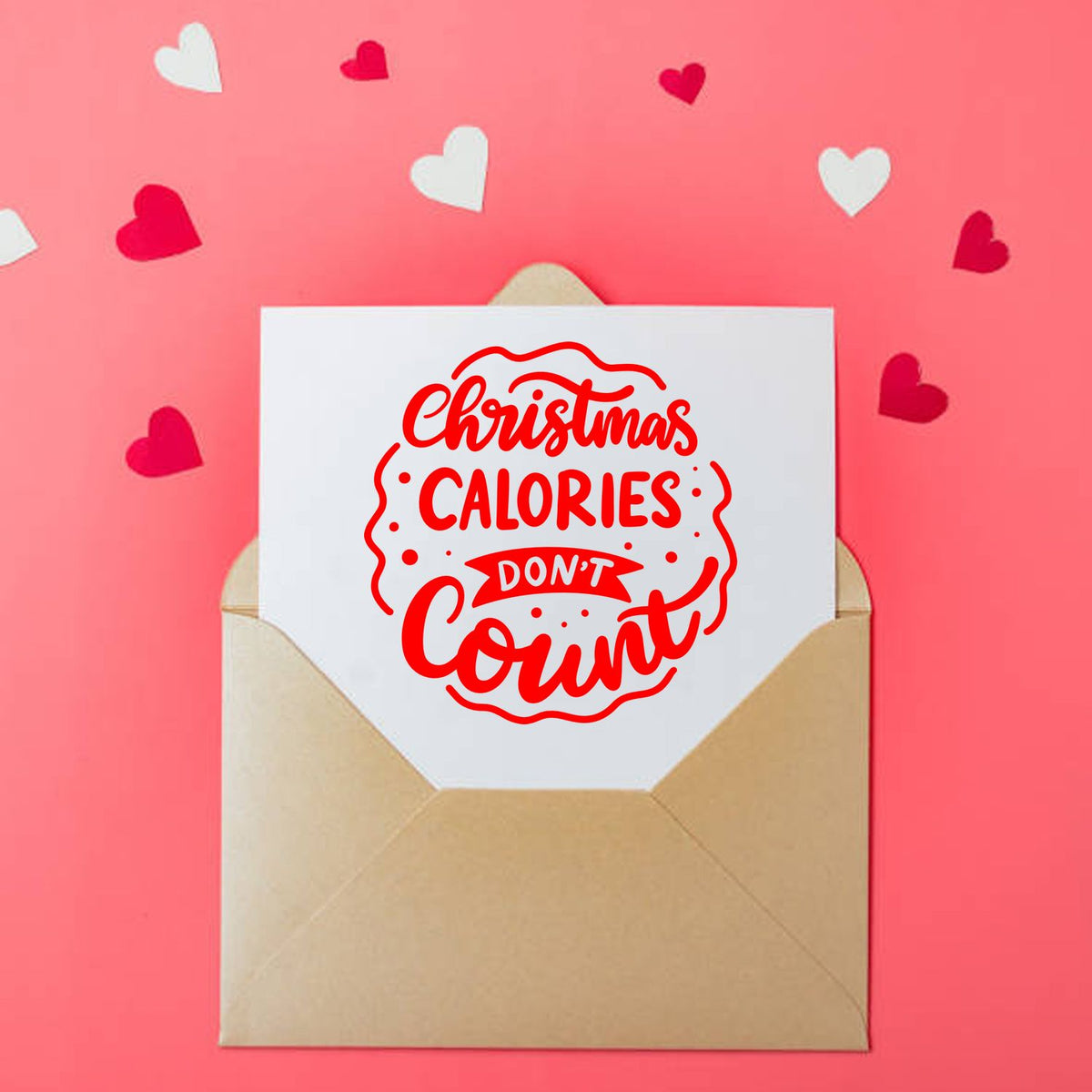Red Christmas stamp seal on white card in tan envelope, pink background with white and red heart confetti.