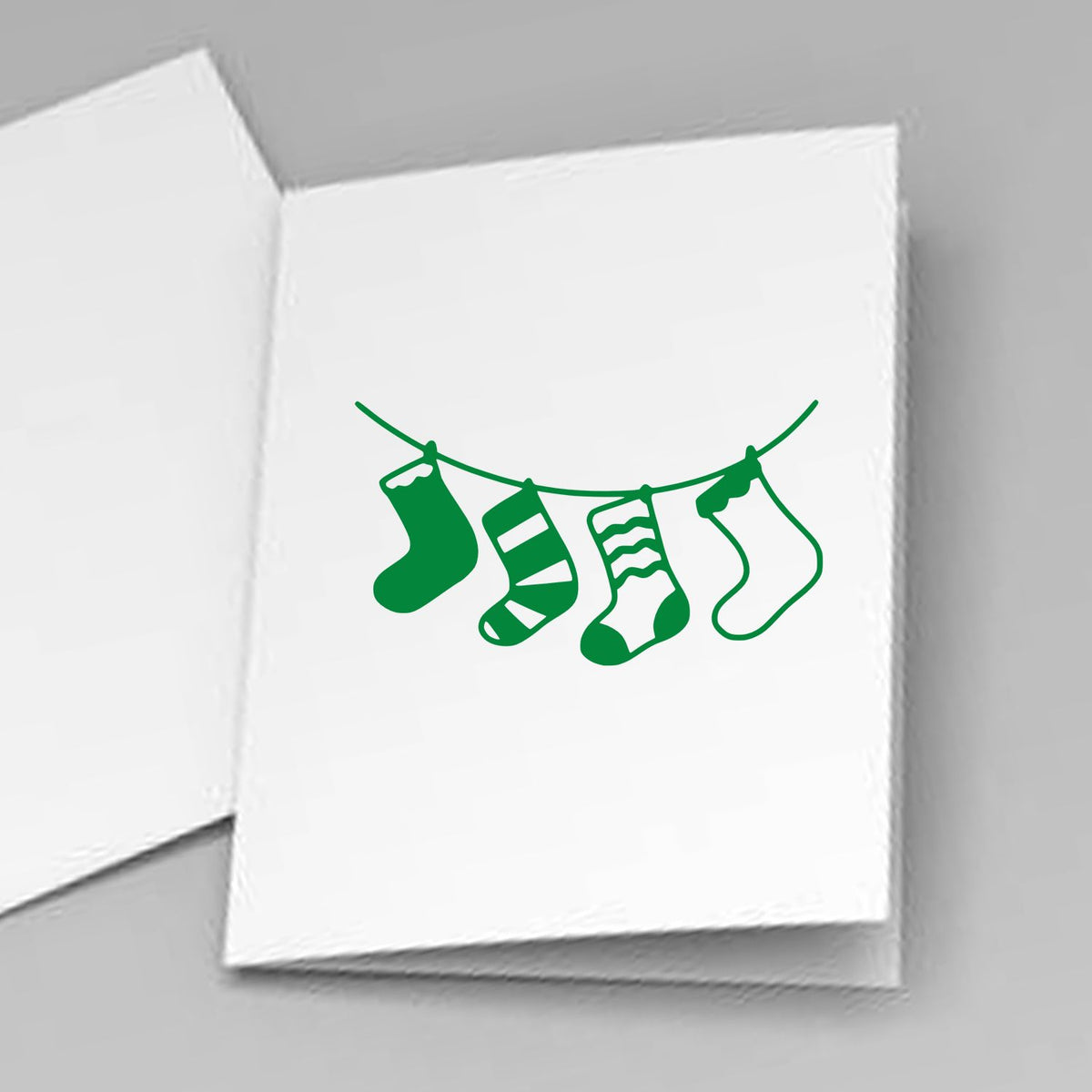 White cards featuring a green holiday stocking stamp and seal design hanging on a line.
