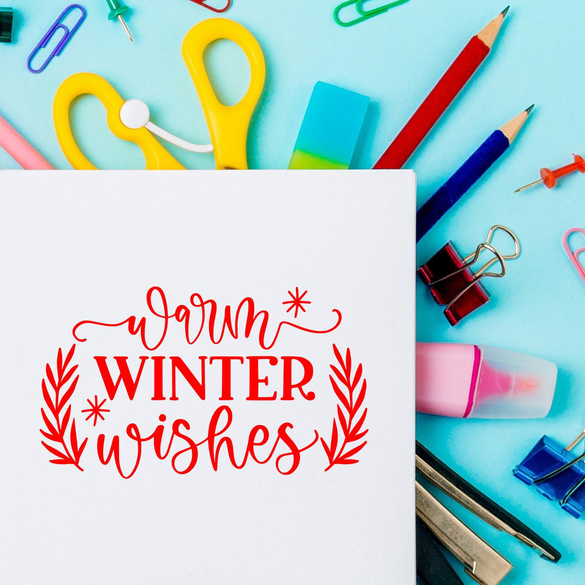 Red warm winter wishes stamp design on a white card, surrounded by colorful stamp and seal stationery on an aqua background.