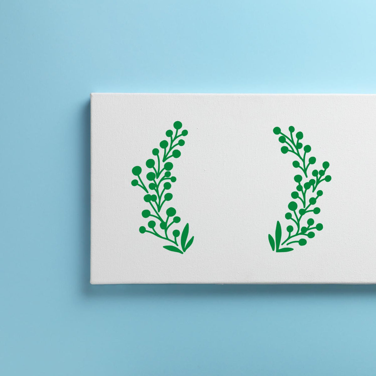 White stamp and seal sample with two green leafy wreath designs on a light blue background.