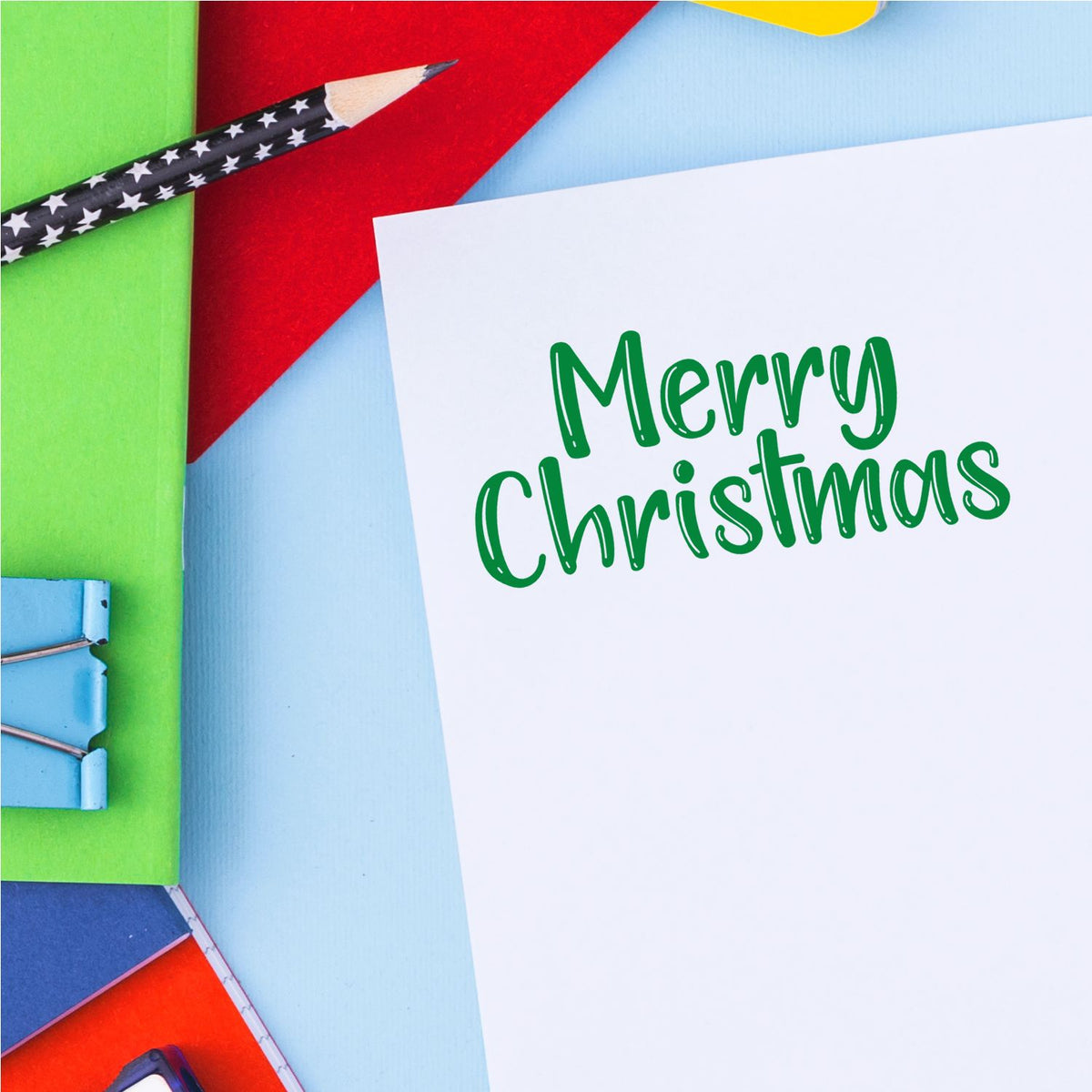 Merry Christmas card with green lettering, star pencil, colorful paper, and stamp-and-seal supplies