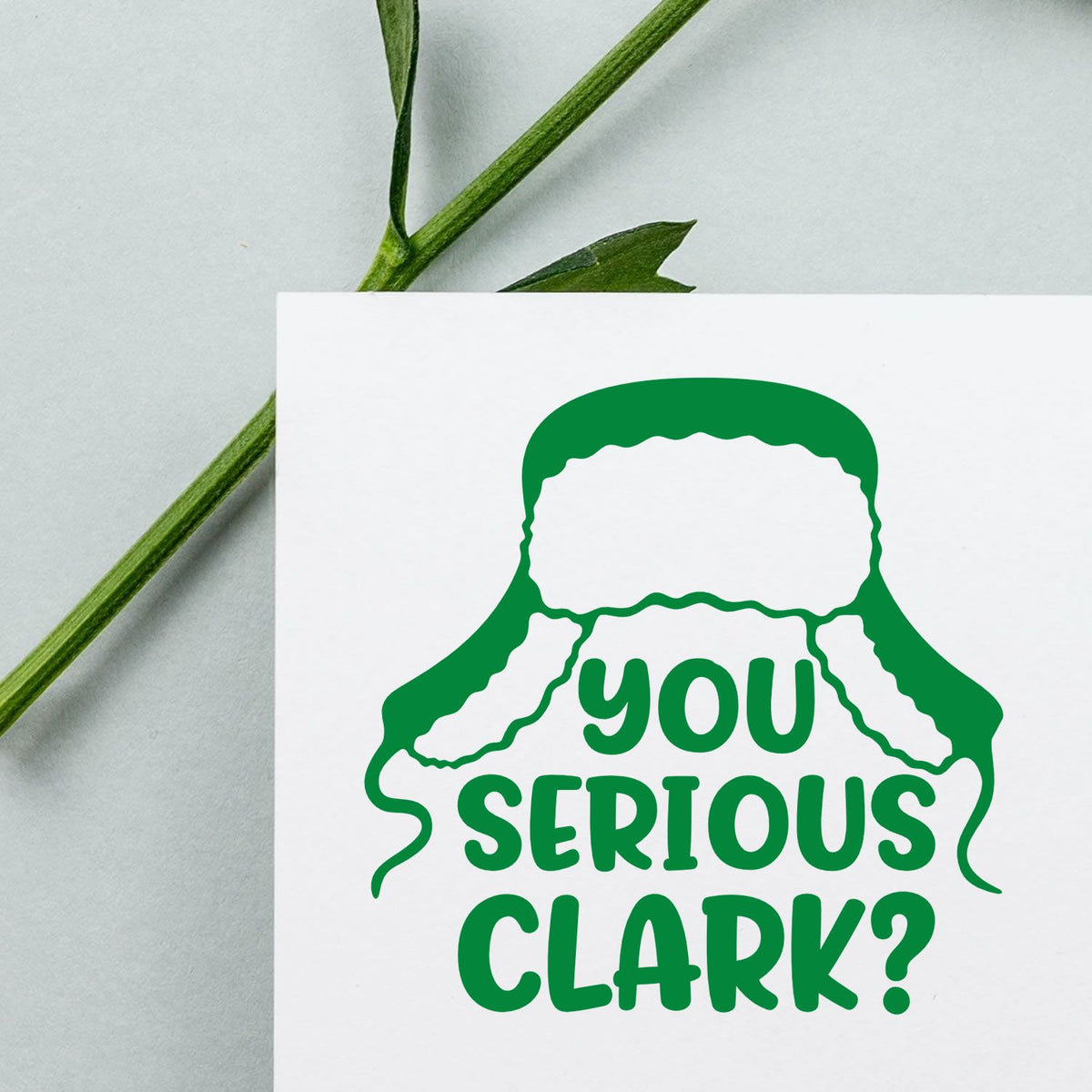 Green rubber stamp seal reading You Serious Clark? on a white card with green leaf stems.