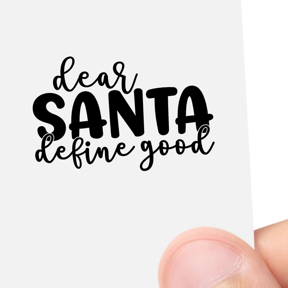 Black custom stamp/seal design reading dear SANTA define good in black on white paper, held by hand.