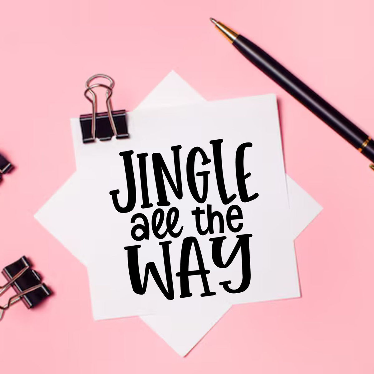 Custom stamp and seal design: black Jingle all the Way lettering on white paper, pink background, binder clip, and black pen.