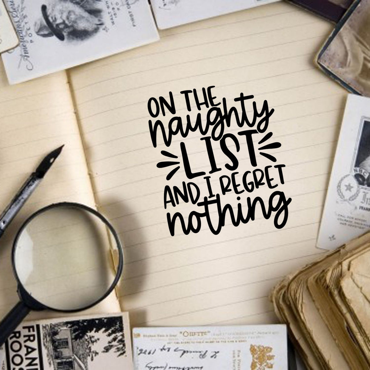 Black hand-lettered quote on a cream notebook, surrounded by vintage stamp and seal products, a magnifying glass, and cream papers.