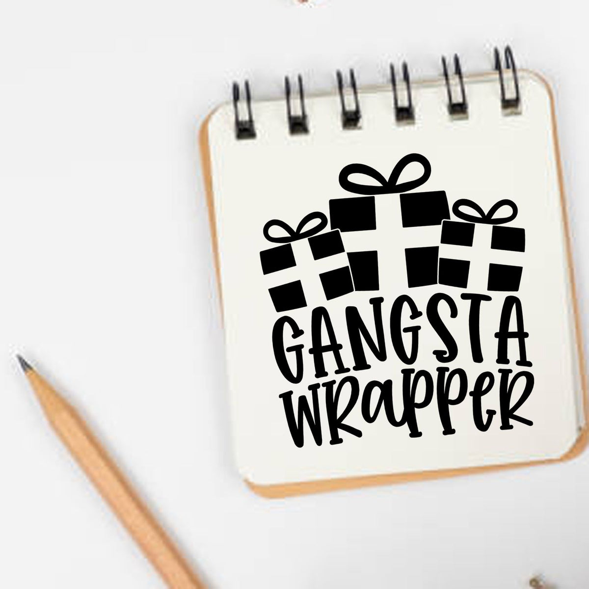 Custom gift stamp and seal design with black Gangsta Wrapper text and present icons on a white notebook.