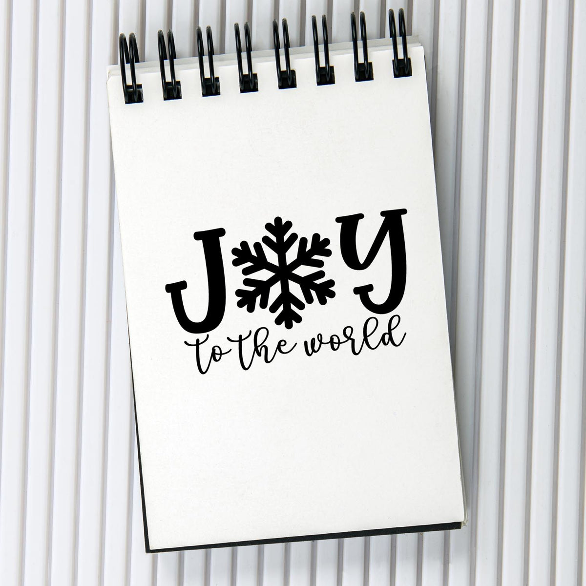 Black holiday stamp and seal on white spiral notebook with snowflake and Joy to the world text