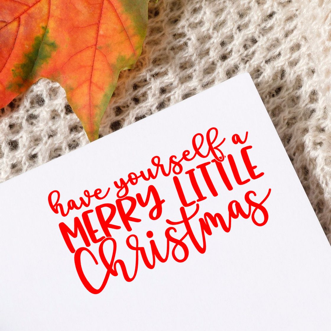 Red Merry Little Christmas stamp/seal on white card, with autumn leaf on cream knit background.