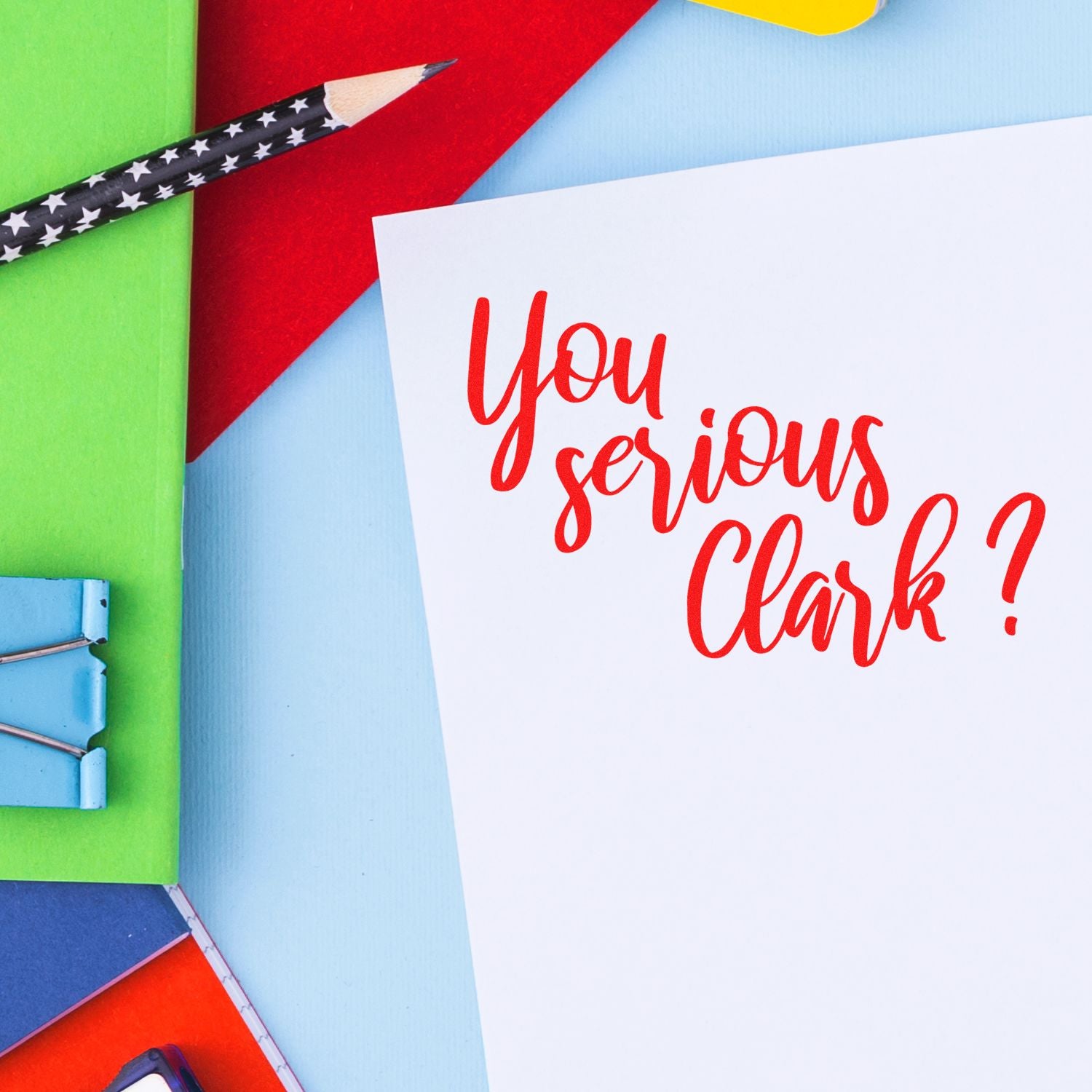 Red You serious Clark? script on white card with colorful stationery, pencils, and clips for stamp and seal products.