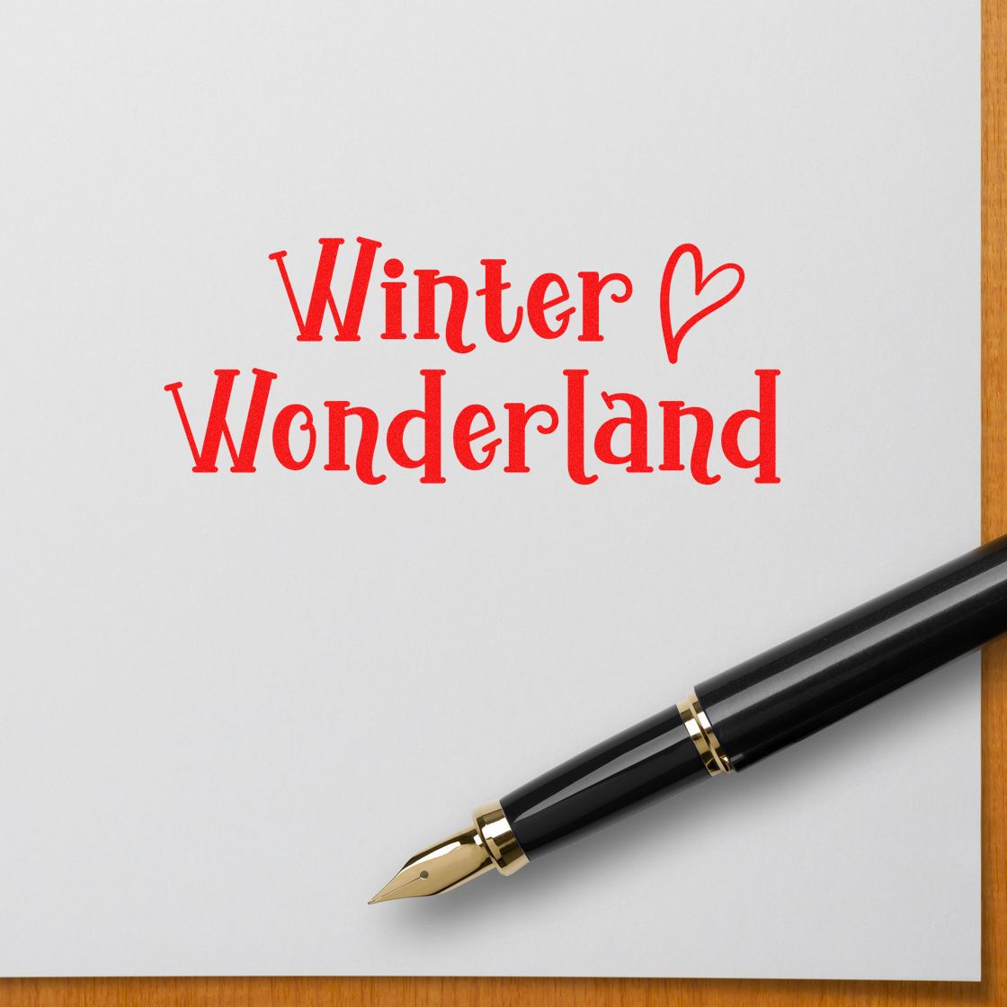 Red Winter Wonderland stamp and seal on white paper beside a black-and-gold fountain pen.