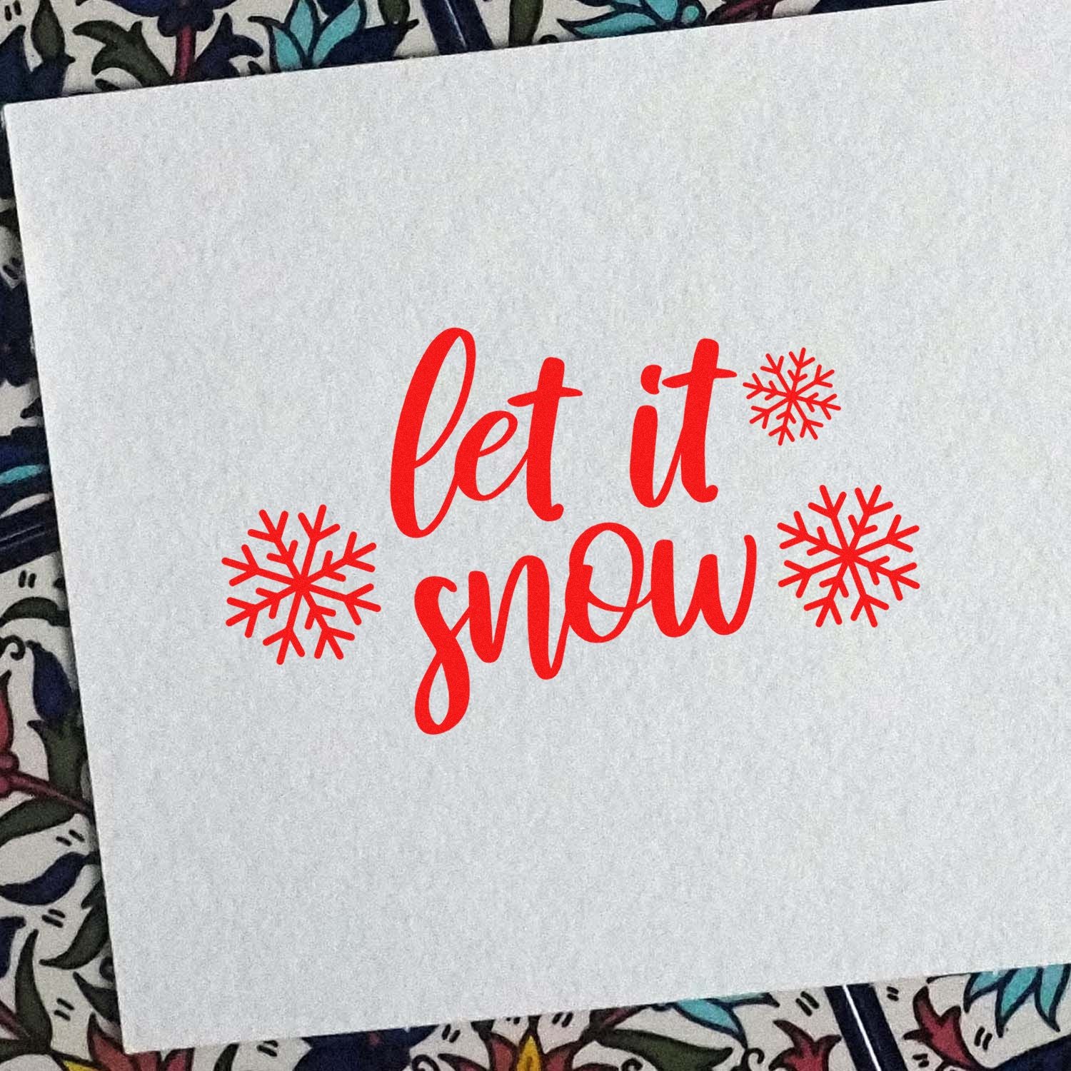 Red let it snow stamp and snowflake seal design in bright red on white paper