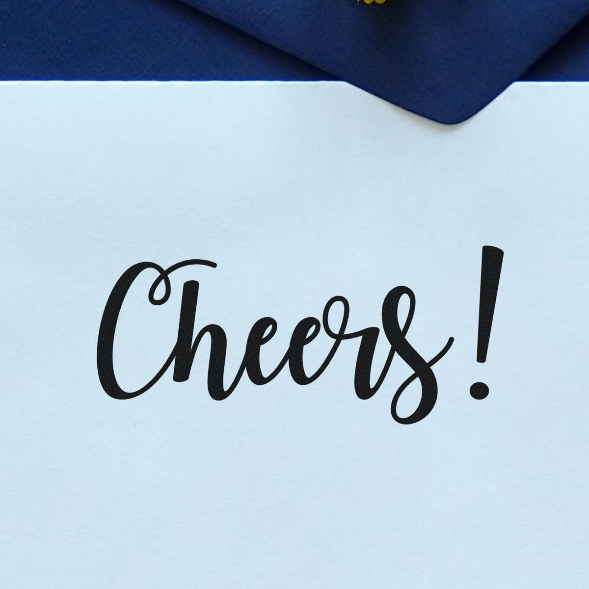 Black Cheers! script stamp on white card with navy envelope flap and seal.