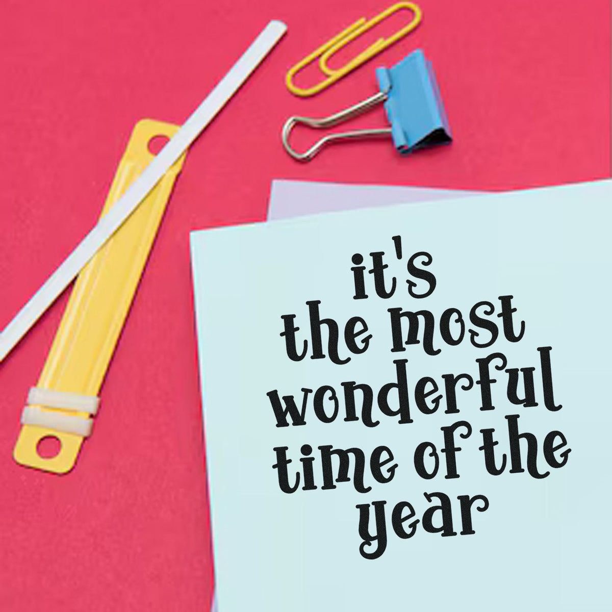Colorful stamp and seal stationery with a light blue card reading "it's the most wonderful time of the year" on a pink background.
