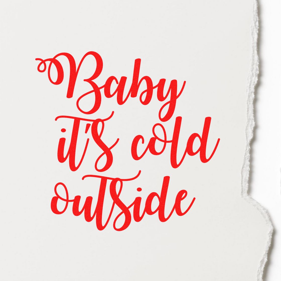 Red cursive stamp and seal reading Baby its cold outside on white torn-edge paper.