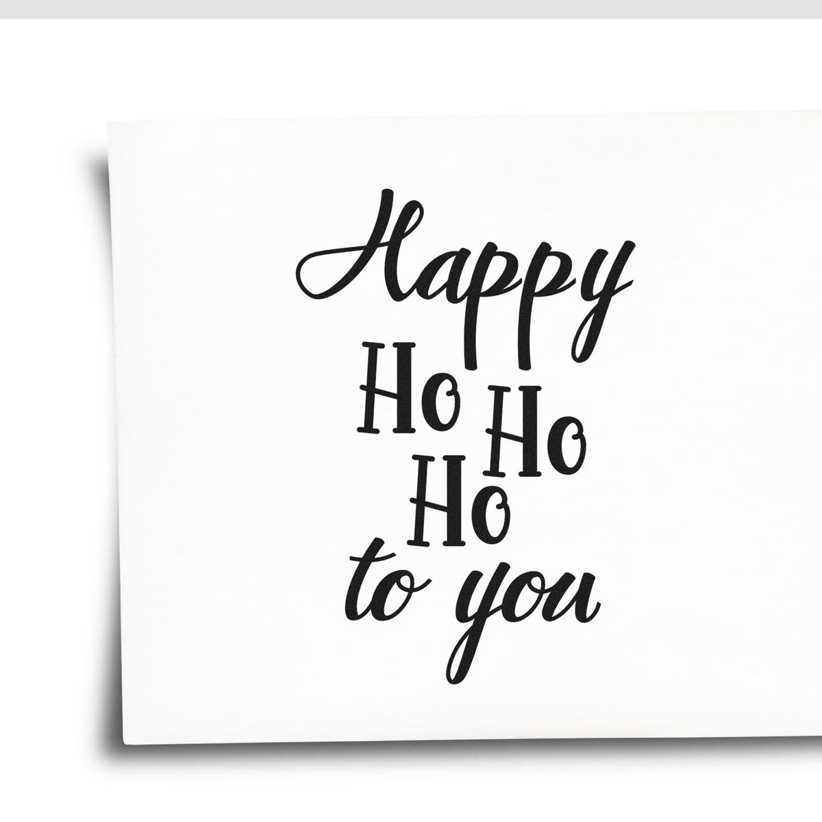 Black holiday stamp seal reading Happy Ho Ho Ho to you on a white card